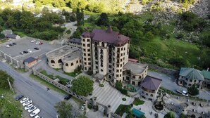 A castle-like building with multiple towers, a parking area, and a surrounding landscaped garden. - Senger Qala Riverside (Ilisu)