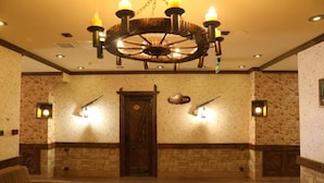 A lobby with a wooden door, stone walls, a chandelier, and a patterned rug. - Senger Qala Riverside (Ilisu)