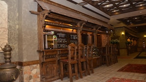 A bar area with wooden furniture and a stone-tiled floor. - Senger Qala Riverside (Ilisu)