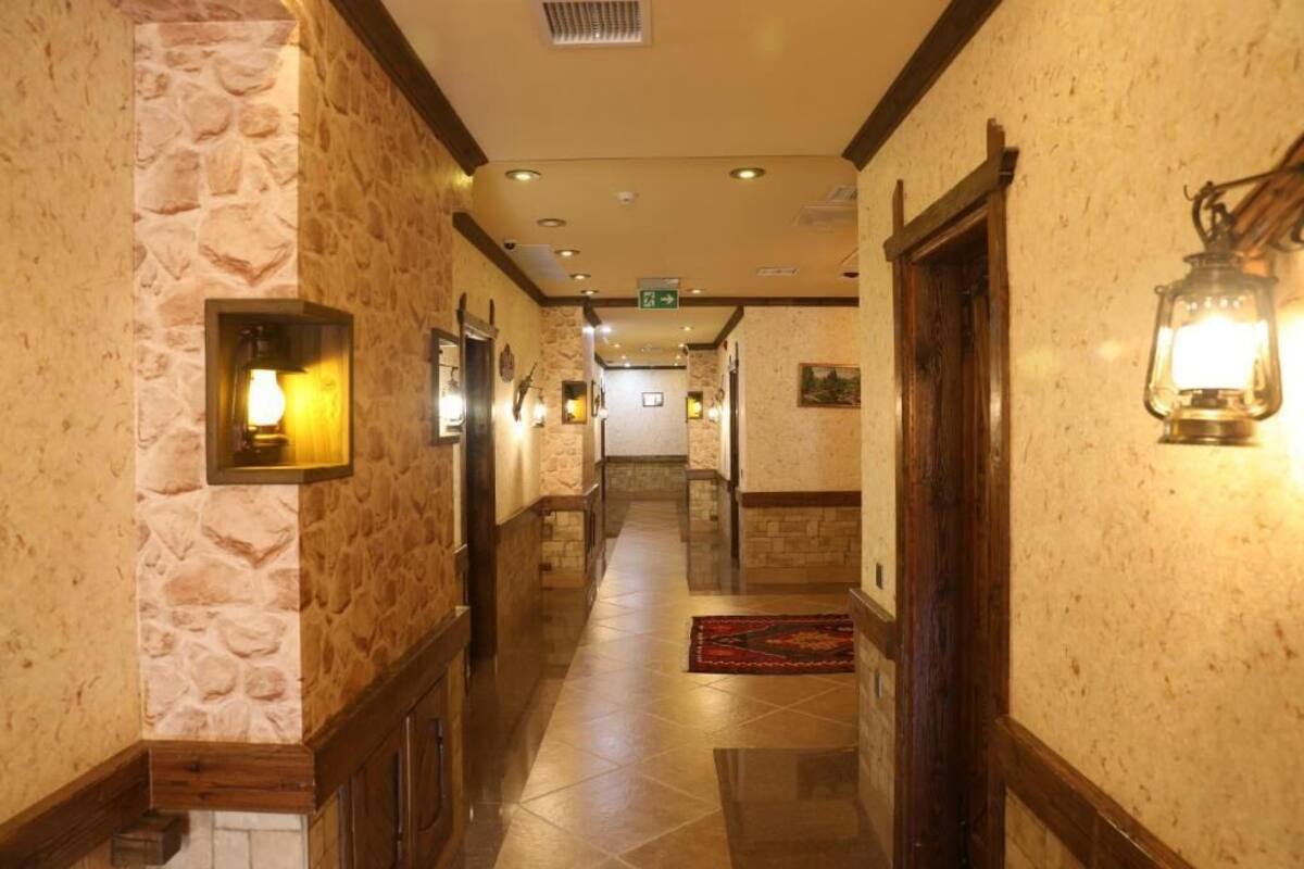 A hotel hallway with stone walls, wooden trim, and a tiled floor.