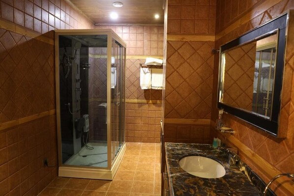 Une salle de bain dotée d’une douche à parois de verre, d’un lavabo avec un plan de travail en marbre et d’un miroir au-dessus du lavabo.