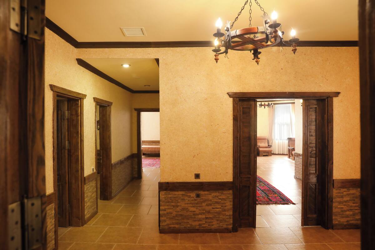 A hallway with wooden doors, a chandelier, and a patterned rug.