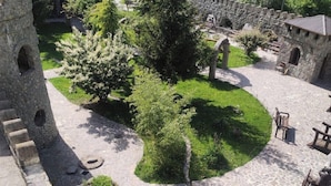 A courtyard with a stone pool, stone buildings, and a large tree. - Senger Qala Riverside (Ilisu)