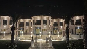 A modern hotel with multiple connected buildings, featuring a central courtyard with seating and a water feature.