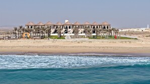 A beachfront hotel with multiple buildings, a pool, and palm trees.