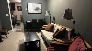 Una sala de estar con un sofá, una mesa de centro, una lámpara y un cuadro en la pared.