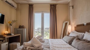 A hotel room with a bed, a desk with a lamp, a television, and a window with curtains. - Alimos Marina Home Luxury Corner SeaView Apartment (Alimos)