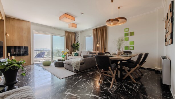 A modern living room with a dining area, large windows, and a view of the city. - Alimos Marina Home Luxury Corner SeaView Apartment (Alimos)