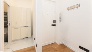 Ein Flur mit einer weißen Tür, einem Kleiderständer und Holzboden.