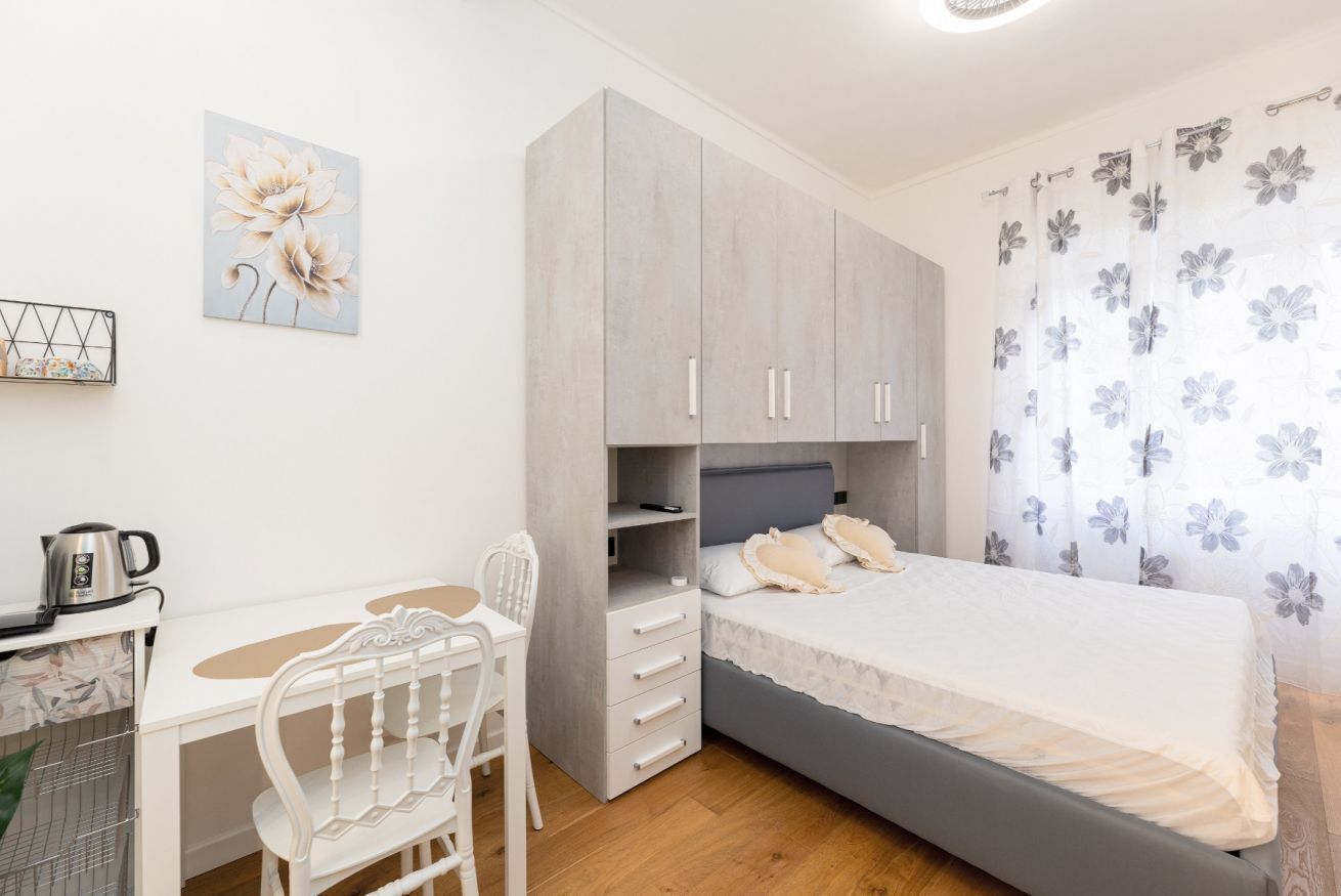 A bedroom with a bed, a desk, and a chair.
