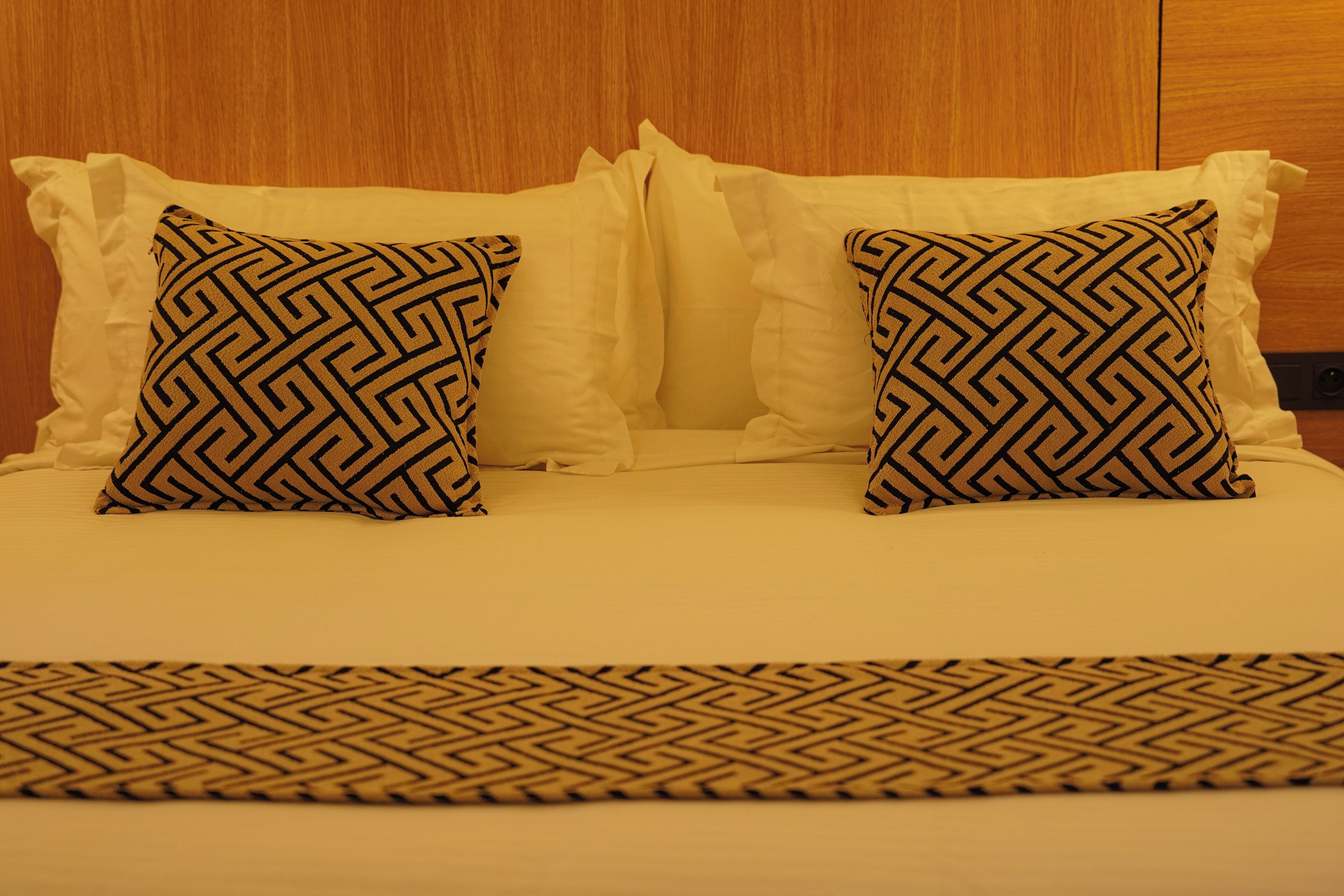 Ein Bett mit zwei gemusterten Kissen und einer passenden Tagesdecke.