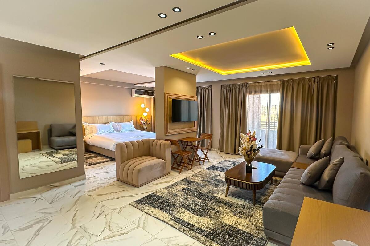 A modern hotel room with a bed, sofa, and a TV.