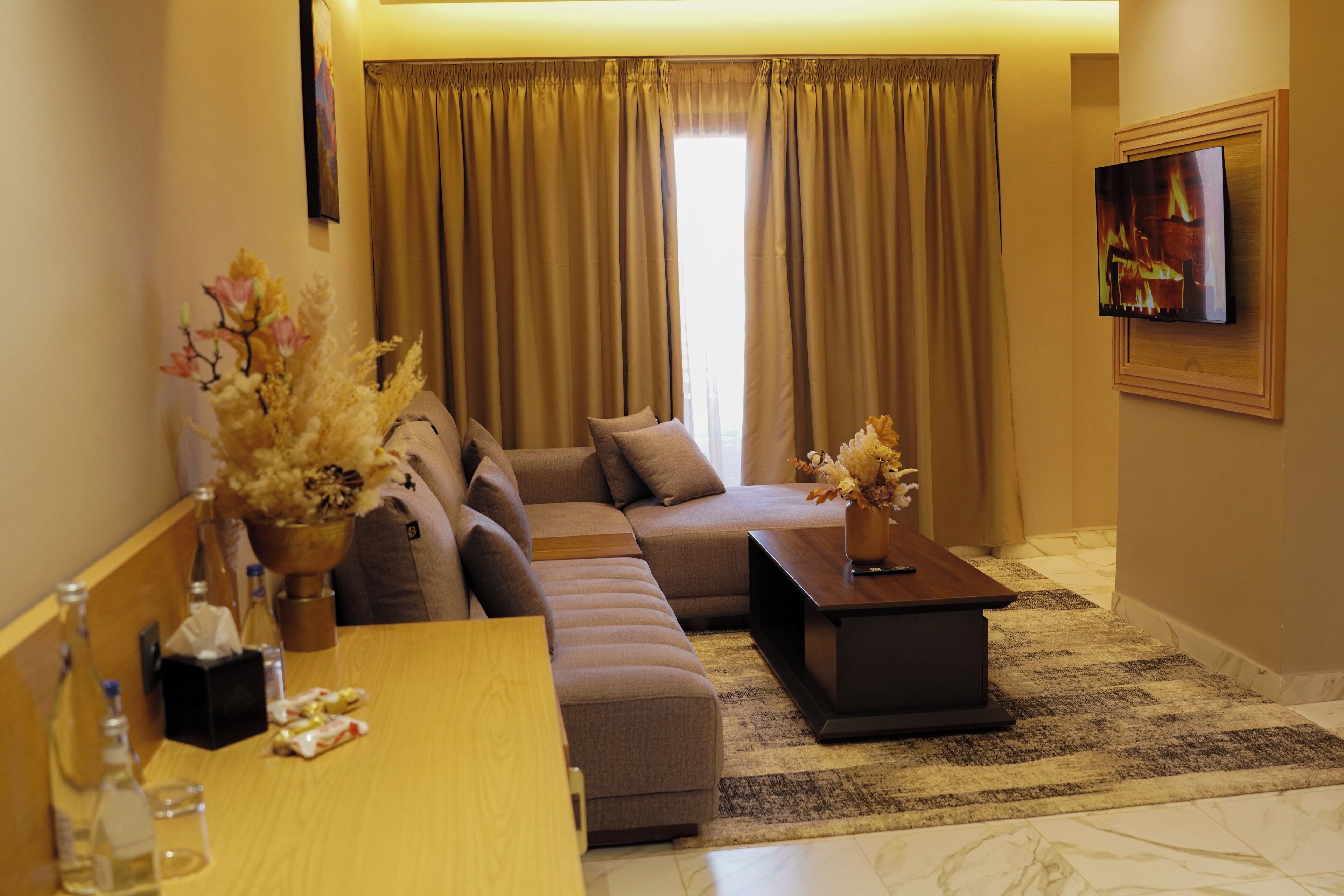 A modern living room with a sectional sofa, a wooden coffee table, and a TV mounted on the wall.