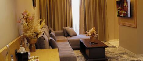 A modern living room with a sectional sofa, a wooden coffee table, and a TV mounted on the wall.