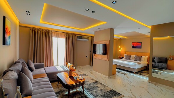 Una habitación de hotel moderna con sofá, una mesita, cama y televisor.