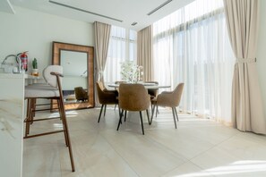 Een moderne eetruimte met een ronde tafel, vier stoelen en een grote spiegel aan de muur.