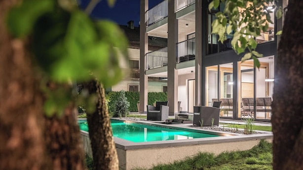 Ein modernes Gebäude mit Pool, Sitzgelegenheiten im Freien und einem gepflegten Garten.
