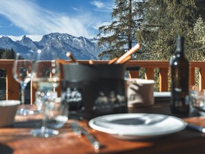 A dining table set outdoors with a mountain view, glasses, a bottle, and a pot. - La Tzoumaz Lodge – Luxury Chalet with Daily Housekeeping, Optional Private Chef (Riddes)