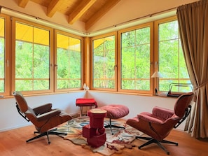A room with large windows, a wooden ceiling, and a red ottoman. - La Tzoumaz Lodge – Luxury Chalet with Daily Housekeeping, Optional Private Chef (Riddes)