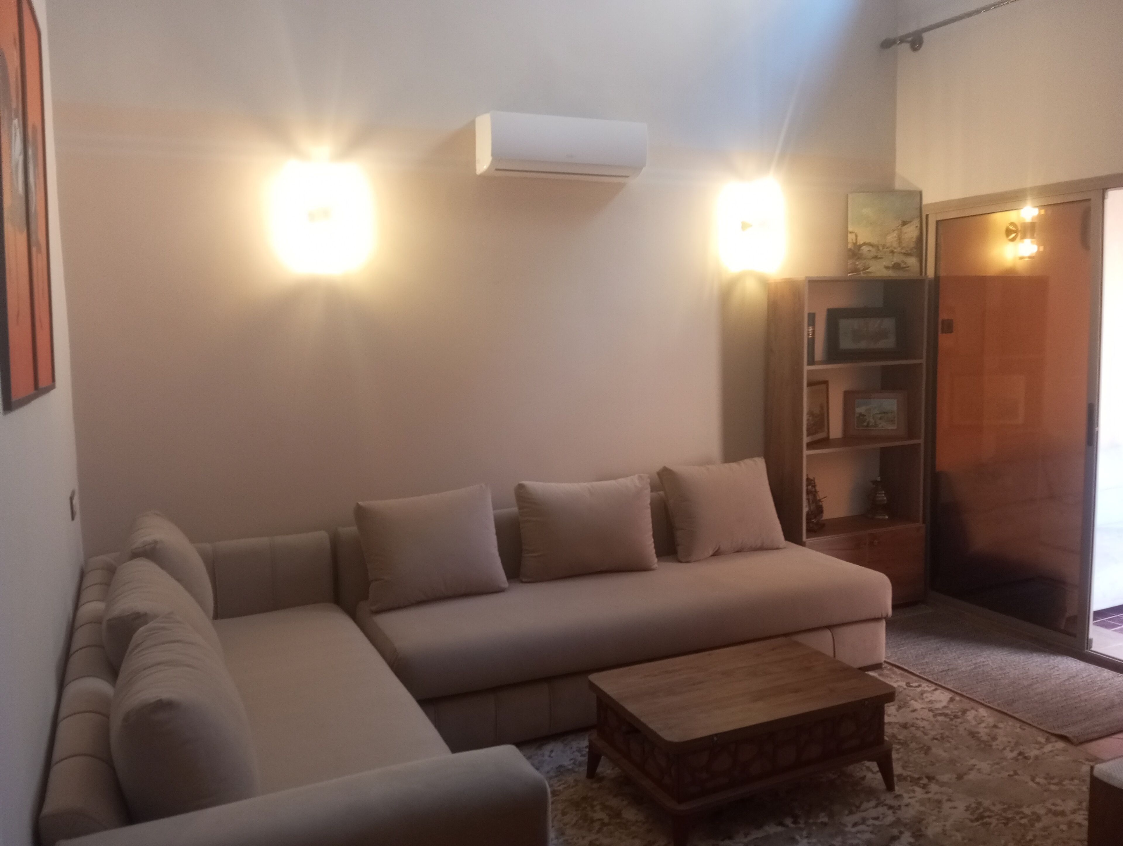 Un soggiorno con un divano modulare beige, un tavolino in legno e una libreria.