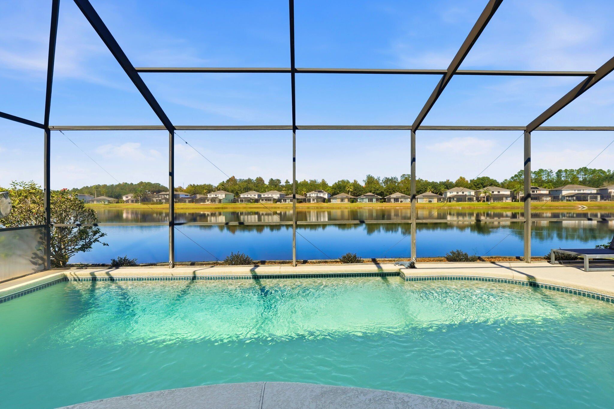 A swimming pool with a view of a lake and houses in the background.