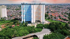 Un edificio alto con fachada azul y blanca, rodeado de una zona residencial densa con casas de tejados rojos.