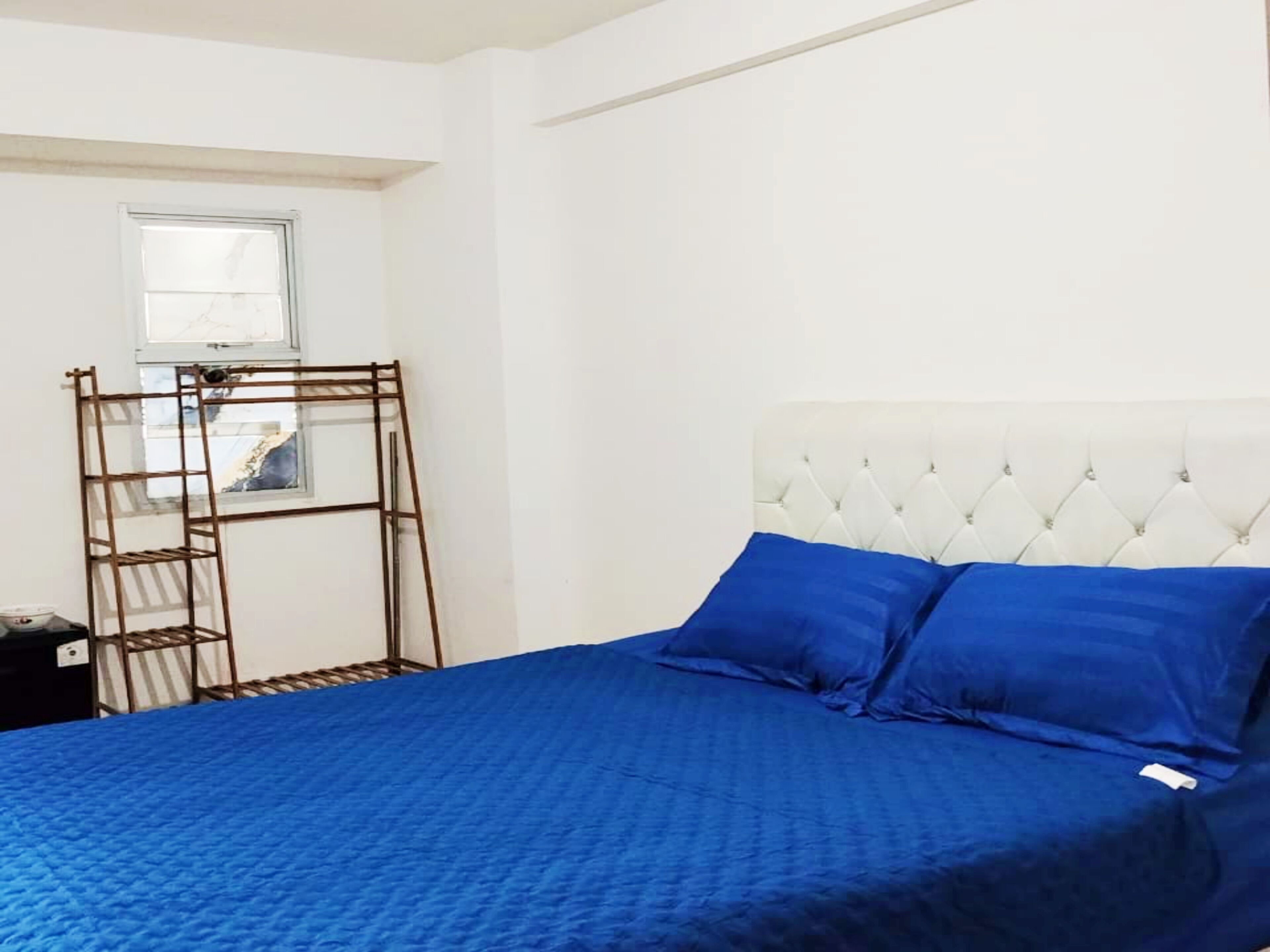 A bedroom with a bed, a window, and a wooden ladder.