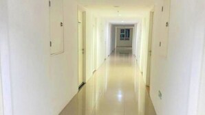 Un pasillo largo y estrecho con paredes blancas y puertas a ambos lados.