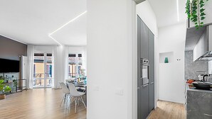 A modern kitchen with a built-in oven and a dining area with a white table and chairs. - Specchio Di Cielo: Apartment With Terrace and AC Arona Center (Arona)