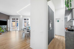 A modern kitchen with a built-in oven and a dining area with a white table and chairs.