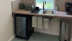 A compact kitchen with a window, a sink, a toaster, a kettle, a small refrigerator, and a trash bin. - Yarck hotel  (Yarck)