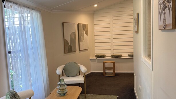 A modern living room with a sofa, a coffee table, and a chair. There are two paintings on the wall, a window with sheer curtains, and a small wooden stool. - Yarck hotel  (Yarck)