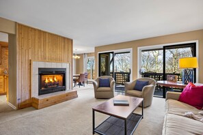 A cozy living room with a fireplace, comfortable seating, and large windows offering a view of the outdoors. - Stoneridge 35 with Wintergreen Advantage (Wintergreen)