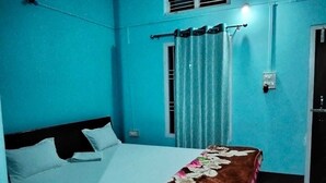 Um quarto com uma cama, uma janela com cortinas e uma porta.