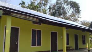 Um edifício amarelo com telhado de chapa metálica, várias portas e janelas.