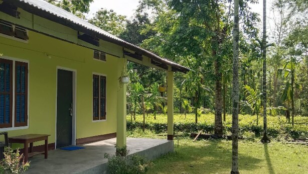 Um edifício amarelo com varanda, porta e janelas.