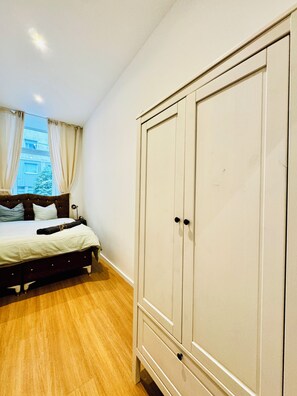 A bedroom with a bed, a wardrobe, and a window with curtains. - Cozy Apartment Near Matzleinsdorfer (Vienna)