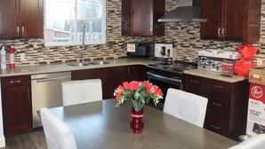A modern kitchen with dark wood cabinets, a tiled backsplash, and a window providing natural light. - Guest Favourite 3BR Home | Walk Downtown | Parking (Fredericton)