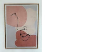 Een lijst met abstract kunstwerk, met een eenvoudige lijntekening van een gezicht en abstracte vormen.