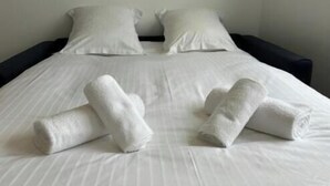 Een bed met witte lakens en opgerolde handdoeken.