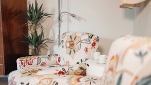 A room with a floral-patterned sofa, a potted plant, and a table with a teapot and cup. - Cozy studio in Porto (Porto)