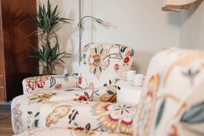 A room with a floral-patterned sofa, a potted plant, and a table with a teapot and cup. - Cozy studio in Porto (Porto)