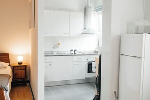 A modern kitchen with white cabinets, a built-in oven, and a refrigerator. - Cozy studio in Porto (Porto)