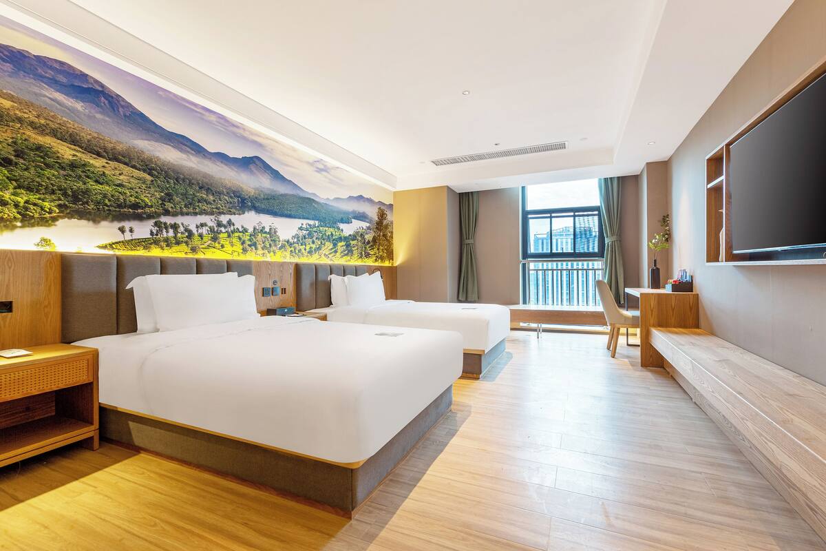A hotel room with a large bed, a desk, and a view of a mountainous landscape.