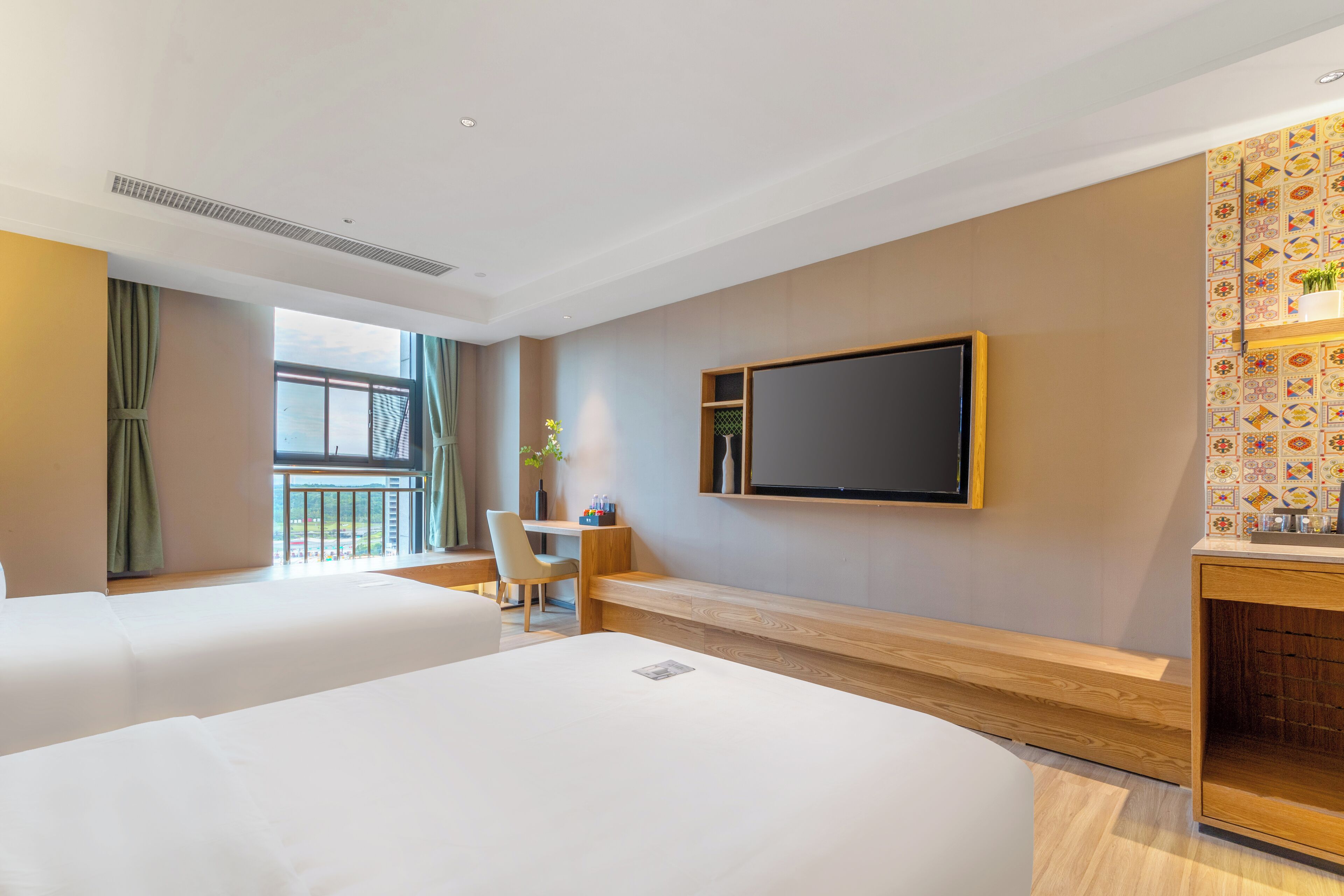 Habitación de hotel con dos camas, un escritorio, una silla, un televisor montado en la pared y un balcón con vistas.