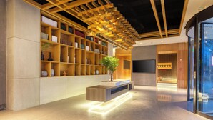A modern interior with a wooden bookshelf, a central console table with a plant, and a glass door leading outside. - TRUE Go hotel (Chengdu)