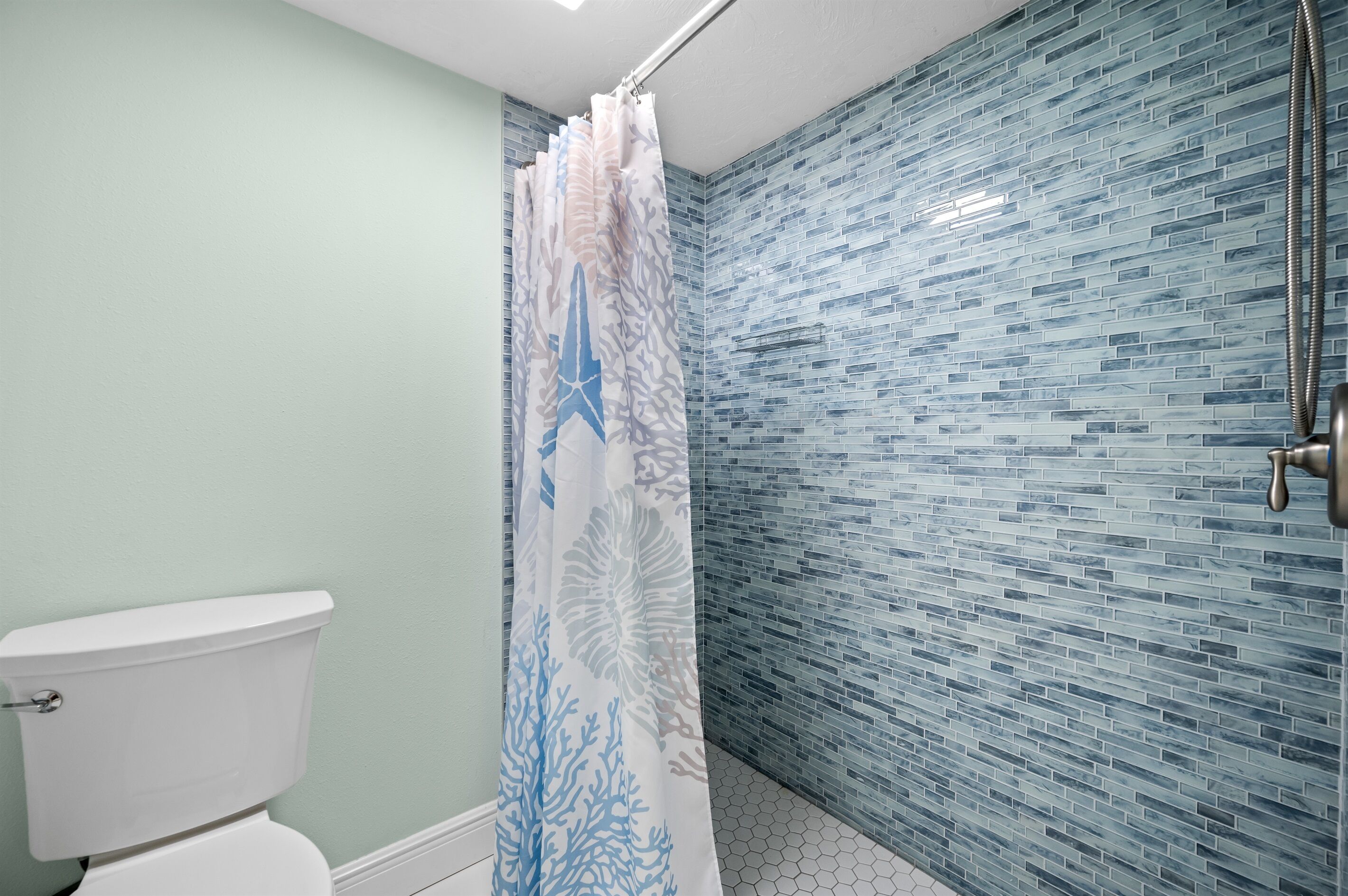 Baño con inodoro, cortina de ducha y paredes de azulejos.