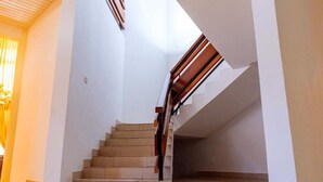 A staircase with wooden handrails and beige steps, leading to a landing with a sloped ceiling and a window. - The Victory Residence is nestled at the heart of East Legon, Accra, Ghana. (Accra)