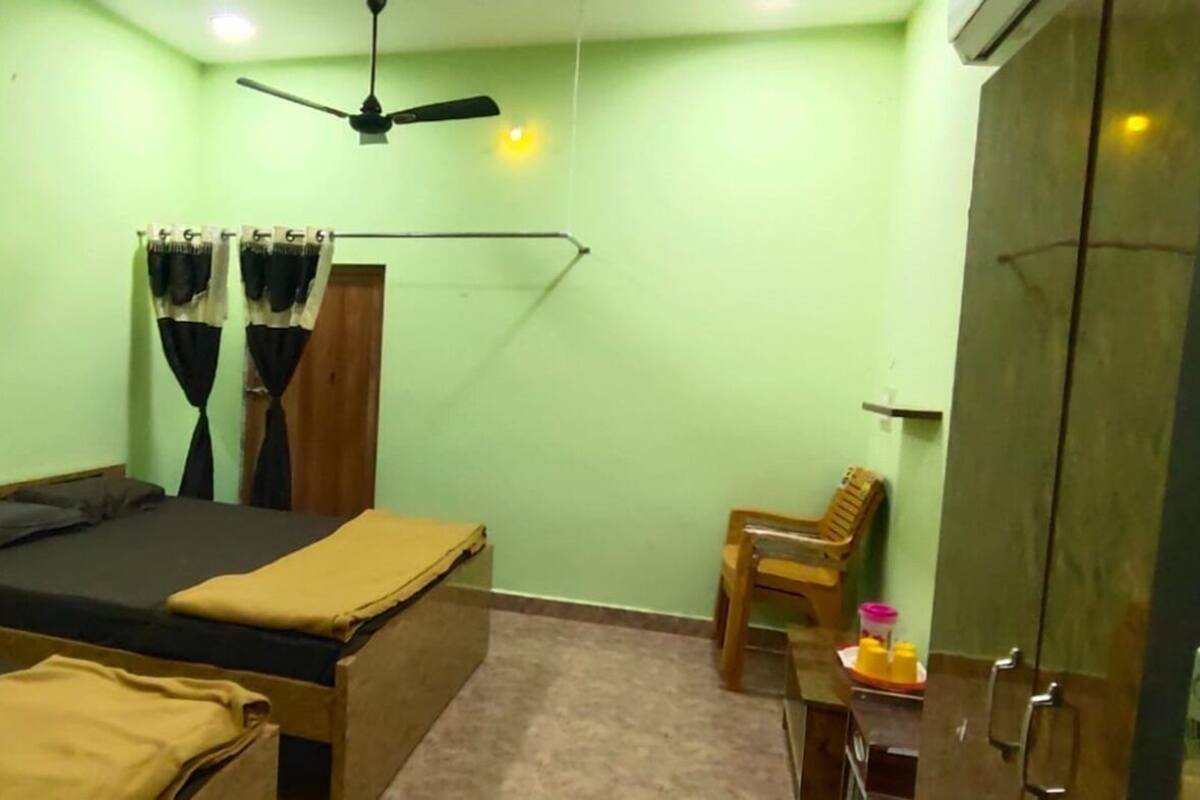 A room with two beds, a ceiling fan, a wooden chair, and a wardrobe.