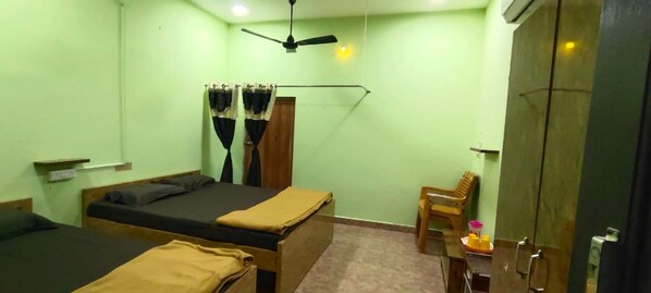 A room with two beds, a ceiling fan, a wooden chair, and a wardrobe. - Thashmika Residency (Tiruvannamalai)